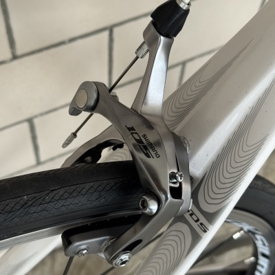 Travão dianteiro Shimano 105 em bicicleta branca com padrões ondulados cinzentos