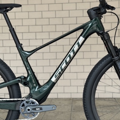 Bicicleta de montanha Scott verde escuro com quadro metálico e pneus pretos.