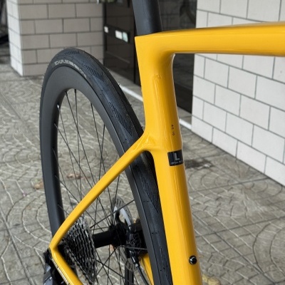 Parte traseira de bicicleta estrada amarela com pneu preto e estrutura de carbono