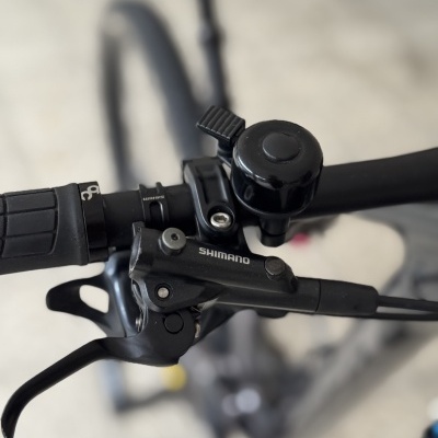 Manete de travão Shimano preta, campainha preta e punho preto no guiador de bicicleta