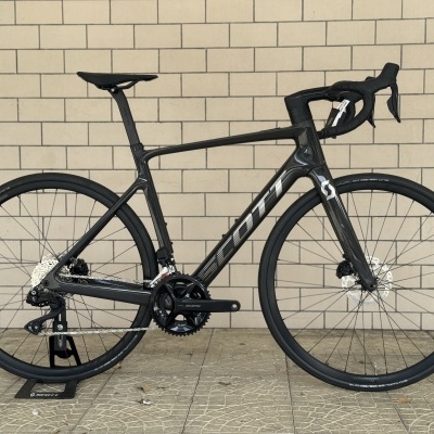 Bicicleta de estrada preta de carbono com rodas finas e componentes Shimano 105.