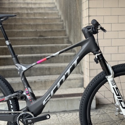 Bicicleta de montanha preta e cinzenta com detalhes rosa e suspensão dianteira branca