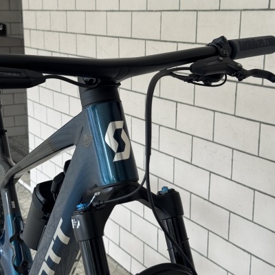 Bicicleta de montanha azul metálica e preta com guiador preto em ambiente interior