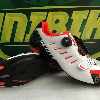 Sapatilhas de ciclismo brancas com detalhes em vermelho e preto e botões de ajuste.