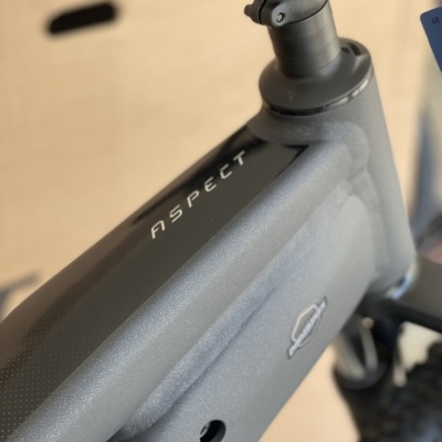 Bicicleta elétrica cinza mate com texto ASPECT no tubo superior