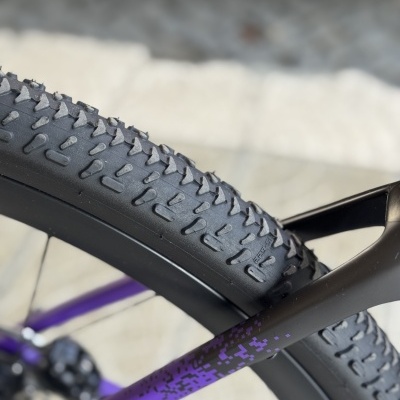 Pneu preto de bicicleta com pneu a céu aberto e quadro preto e roxo.