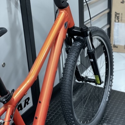 Bicicleta laranja com pneus pretos em superfície antiderrapante