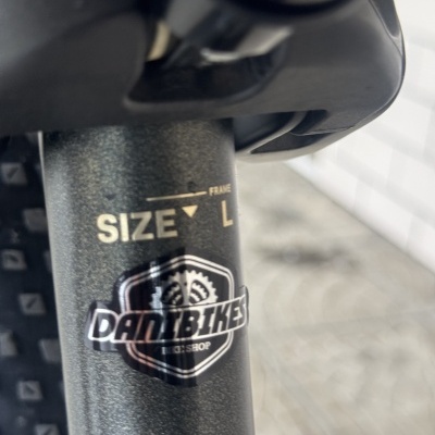 Estrutura metálica cinzenta de bicicleta com autocolante DANIBIKES e texto SIZE L FRAME