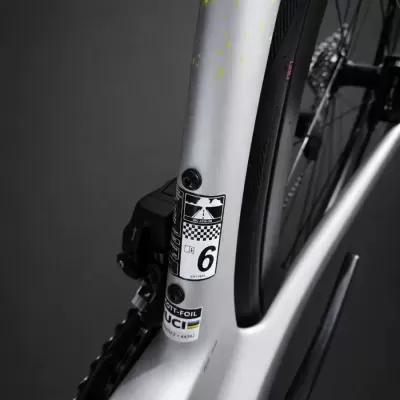 Detalhe do quadro de bicicleta branca com adesivos e pneu preto