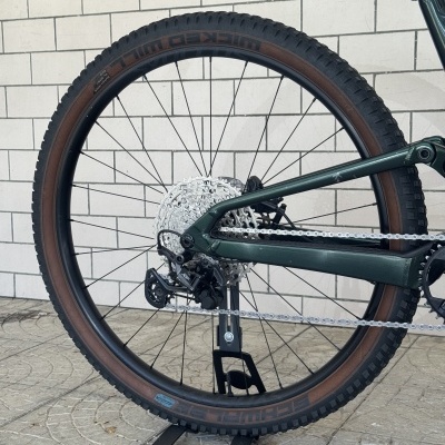 Roda traseira de bicicleta de montanha com pneu preto e castanho e quadro verde escuro