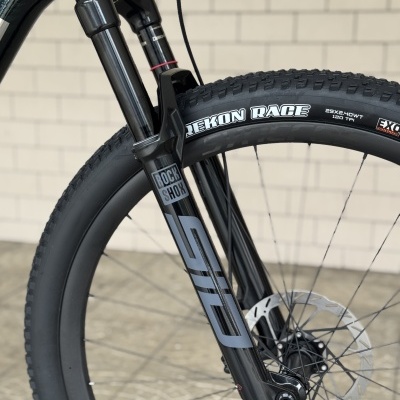 Roda de bicicleta com pneu preto, garfo dianteiro Rock Shox e disco de travão