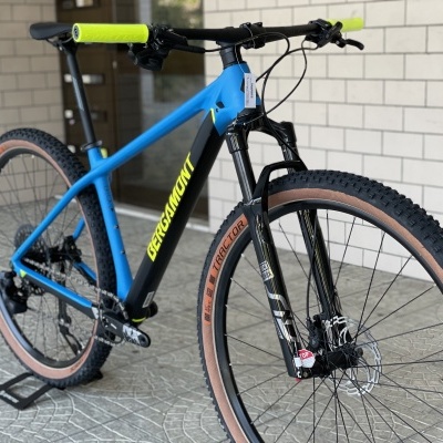 Bicicleta de montanha azul e preta com punhos verdes e pneus castanhos