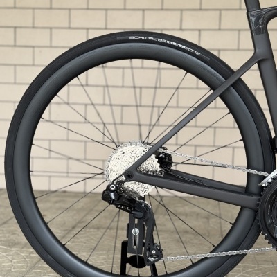 Roda traseira de bicicleta com aro e pneu pretos em fundo de parede de tijolos