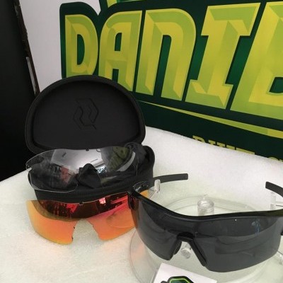 Dois óculos de sol desportivos com lentes de cores diferentes e armação preta em fundo com logo DANIBIKES.