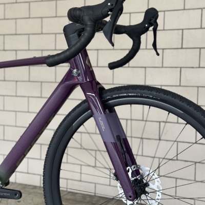 Bicicleta roxa com guiador preto e pneus Schwalbe G-One Bite