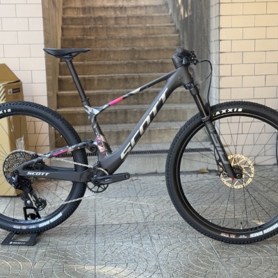 Bicicleta de montanha preta e cinza SCOTT com pneus Maxxis e disco de travão dourado