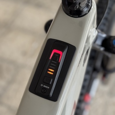 Bicicleta elétrica branca com indicador de bateria Bosch no tubo superior.