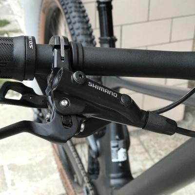 Maneta de travão preta Shimano numa bicicleta preta com piso e parede ao fundo