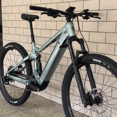 Bicicleta de montanha elétrica cinza claro junto a uma parede de azulejos bege