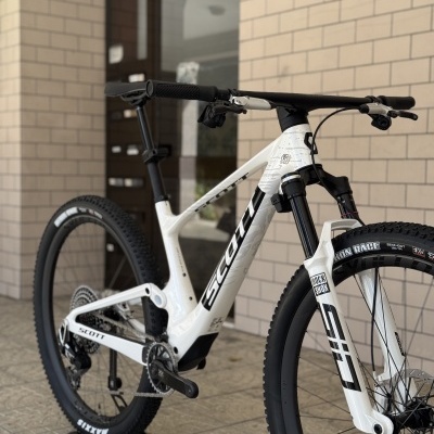 Bicicleta de montanha SCOTT branca com pneus Maxxis Race num chão de mosaico junto a parede de azulejos