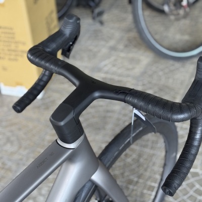 Bicicleta de estrada cinzenta com guiador preto em ambiente interior