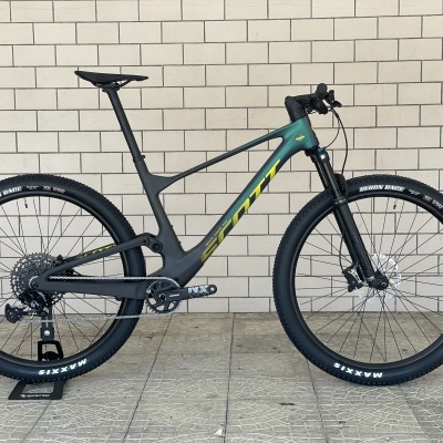 Bicicleta de montanha SCOTT cinza com pneus pretos em parede de tijolos branca