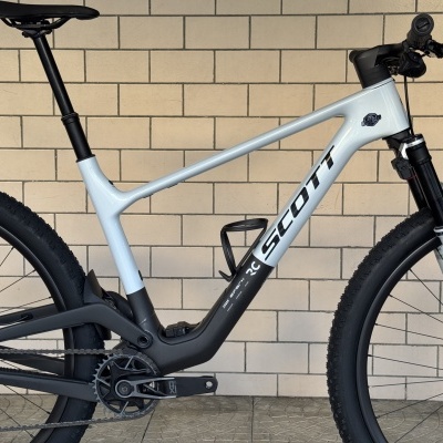 Bicicleta de montanha branca e preta Scott Spark RC contra parede de tijolos claros