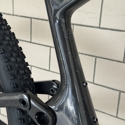 Peça preta brilhante de bicicleta com escrita PRANIER e parte do pneu com padrão de cravos