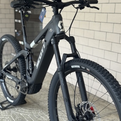 Bicicleta de montanha elétrica preta SCOTT com pneus REKON e suspensão dianteira em loja