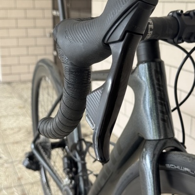 Bicicleta de estrada cinza com guiador preto e manete Shimano
