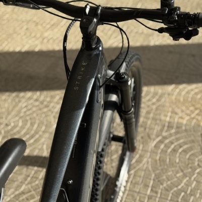 Bicicleta elétrica preta com texto STRIKE e suspensão dianteira