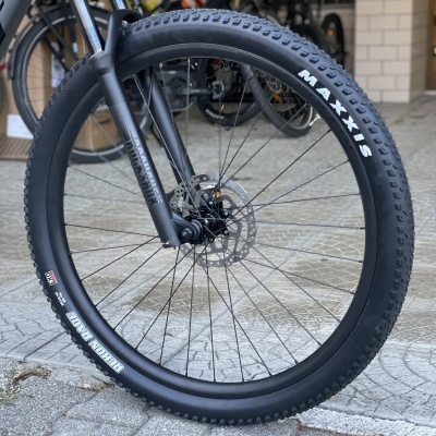 Pneu de bicicleta de montanha preto com texto MAXXIS e detalhes visíveis no aro e na roda