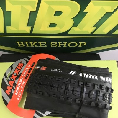 Pneu de bicicleta Maxxis Minion DHR II preto com etiqueta vermelha sobre mesa amarela