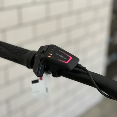 Controlador Bosch para bicicleta elétrica preto montado em guiador preto com parede branca ao fundo