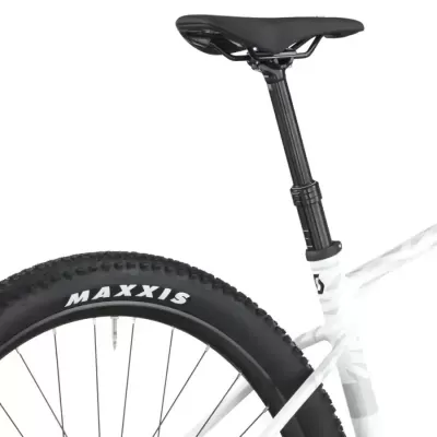 Banco de bicicleta preto com pneu Maxxis preto montado em quadro branco.