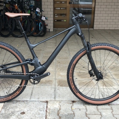 Bicicleta montanha preta com pneus castanhos e suspensão dianteira