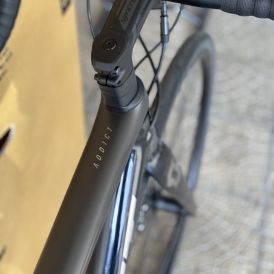 Bicicleta de estrada preta fosca com texto ADDICT no quadro e guiador preto