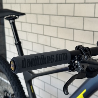 Punhos de espuma preta de bicicleta com gravação danibikes.com e componente de travão XTR em bicicleta cinza escuro