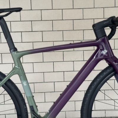 Bicicleta de estrada com quadro verde e roxo e detalhes pretos