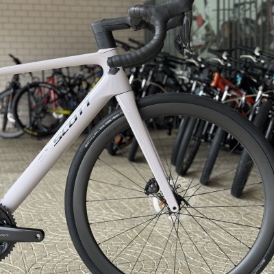 Bicicleta de estrada branca com guiador preto e roda dianteira larga