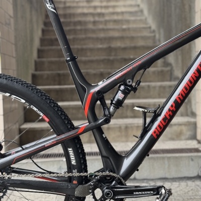 Quadro de bicicleta de montanha preta e vermelha com suspensão e rodas visíveis