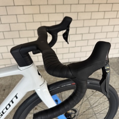 Bicicleta branca de estrada com guiador curvo preto e fita texturizada