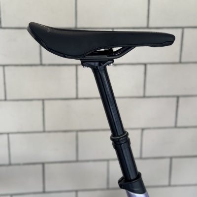 Banco de bicicleta preto e haste regulável contra fundo de azulejos brancos