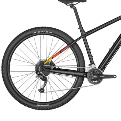Roda traseira de bicicleta preta com aro KENDA e quadro preto com detalhes em vermelho e amarelo.