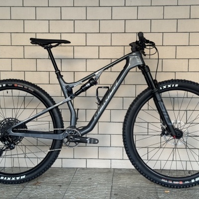 Bicicleta de montanha cinzenta com pneus pretos Maxxis Minion DHR II e suspensão RockShox