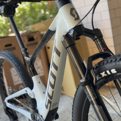 Bicicleta de montanha SCOTT branca e preta com pneus Maxxis em ambiente com caixas de cartão