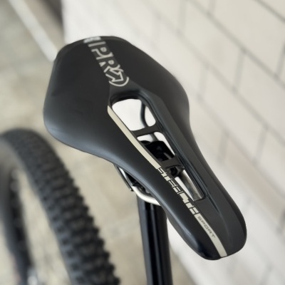 Selim de bicicleta preto com detalhes em branco e cinza, com texto e canote preto