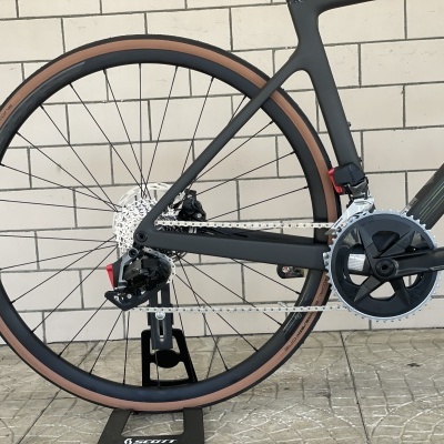 Bicicleta carbono preta com roda traseira e componentes mecânicos detalhados