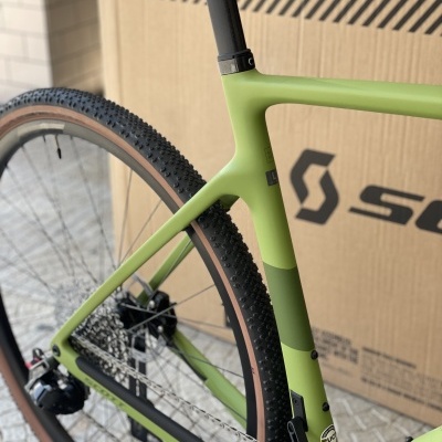 Quadro verde de bicicleta com pneus e corrente, embalagem de cartão ao fundo