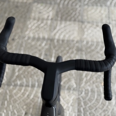 Guiador de bicicleta preto com fita texturada num chão com padrão geométrico cinza